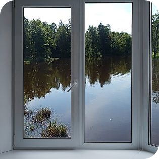 Scenic view of a pond and trees through a modern window.
